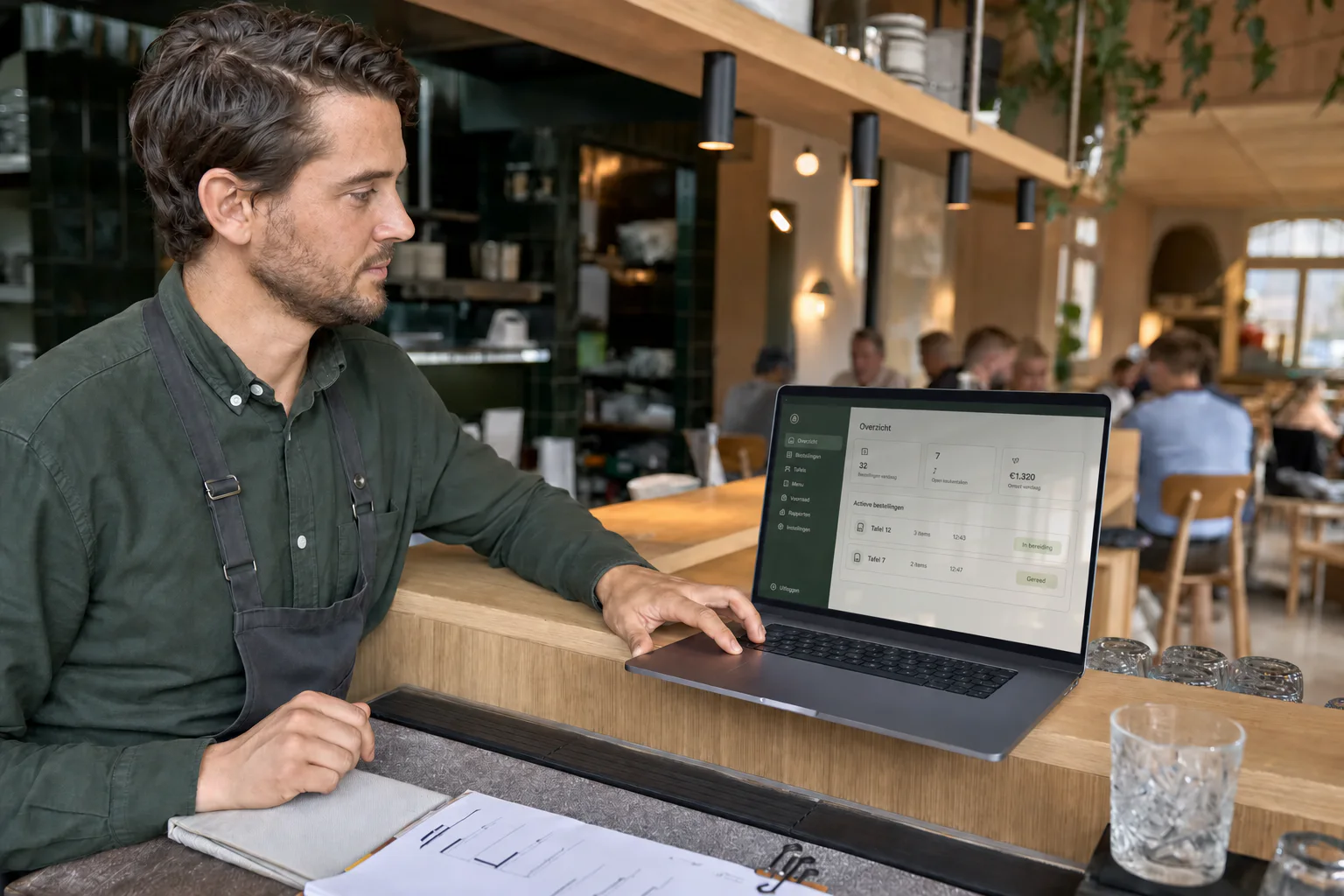 Restaurantmanager bekijkt het WorkTable-dashboard op een laptop bij de servicebalie